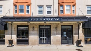 Un immeuble à la façade noire, avec le nom « THE HANSCOM » inscrit au-dessus de l’entrée.