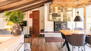 A cozy living area with a fireplace, wooden ceiling beams, and a dining table with chairs. - 4 Star Holiday Home in Hals (Hals)