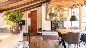 A cozy, well-lit room with a wooden ceiling, a stone fireplace, and a dining area with modern chairs and a table. - 4 Star Holiday Home in Hals (Hals)