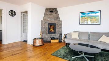 Una sala de estar con chimenea de piedra, un sofá gris, una mesa de centro y un cuadro en la pared.