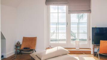 Una habitación con un ventanal grande, una silla, una mesa y un sofá.