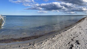 Une plage à l’eau claire, avec un rivage sablonneux et un horizon lointain.