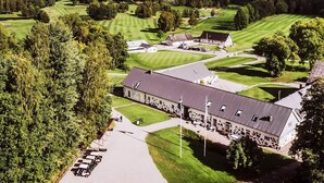 Campo de golf con club house, zona de estacionamiento y vistas a un lago.