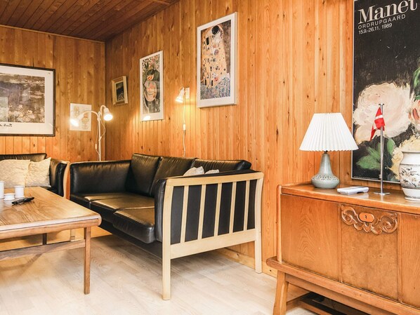 A cozy room with wooden walls, a leather sofa, a wooden table, and a lamp. - 6 Person Holiday Home in Fano (Fano)