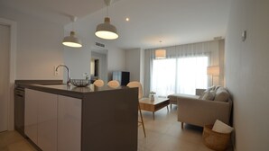 A modern kitchen with a central island, a dining area with a table and chairs, and a living room with a sofa and a TV. - Los Flamencos 6104 - Two Bedroom Apartment, Sleeps 5 (Punta del moral)