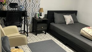 Une chambre à coucher avec un lit, un bureau, une chaise, une table de chevet et un rideau à motifs.