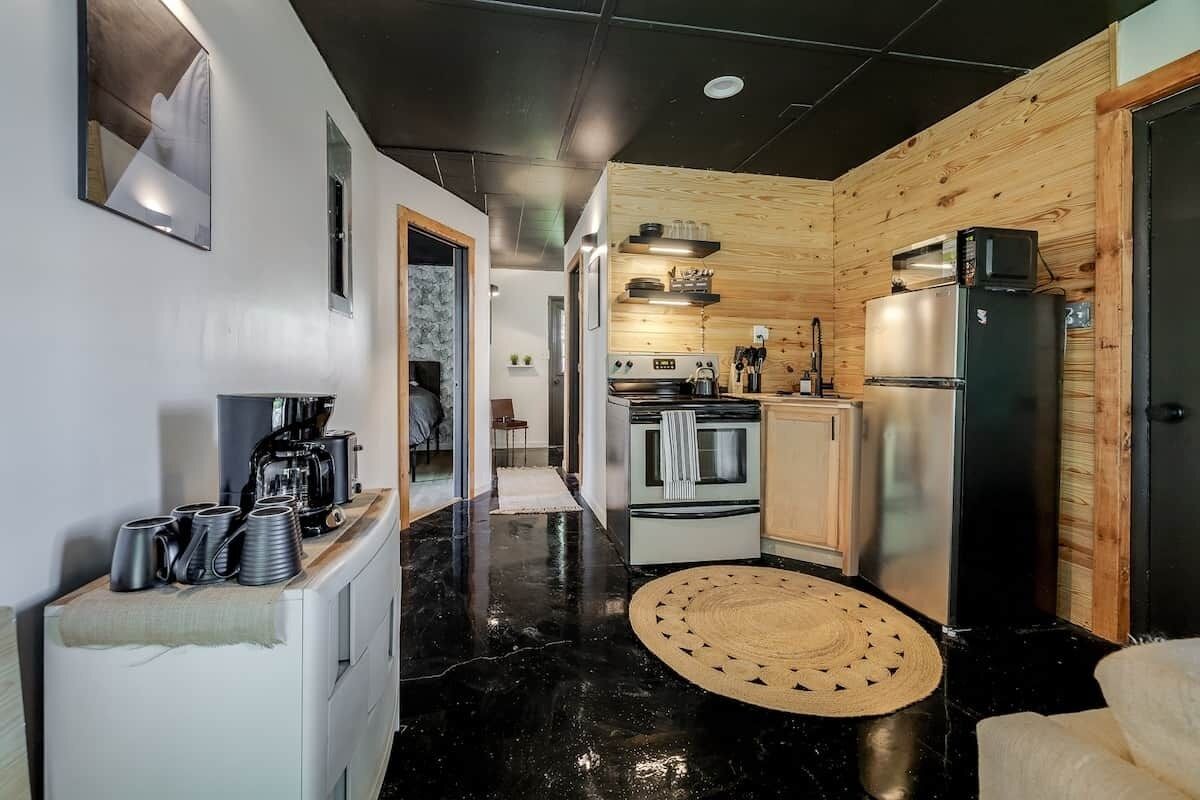 A modern kitchen with wooden accents, a coffee machine, and a refrigerator.