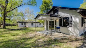 Een modern gelijkvloers huis met een overdekte patio, een barbecue en een kleine tuin.