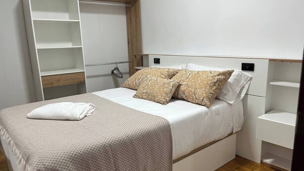 Un dormitorio con cama, armario y perchero.