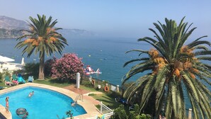 Une piscine avec vue sur la mer, des palmiers et un toboggan.
