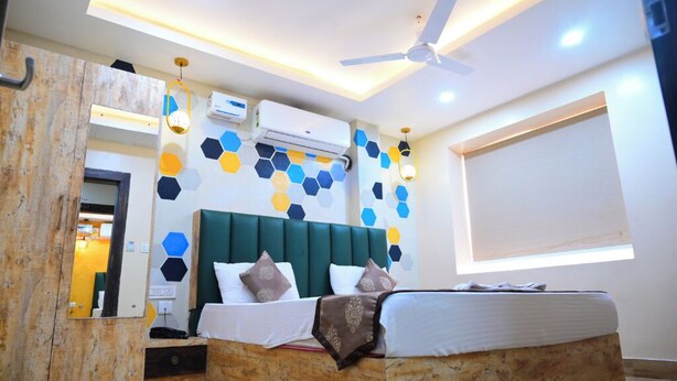 A modern bedroom with a large bed, a ceiling fan, and a wall with hexagonal patterns. - DhamStay Hotel Santosh Inn Near Temple (Puri)