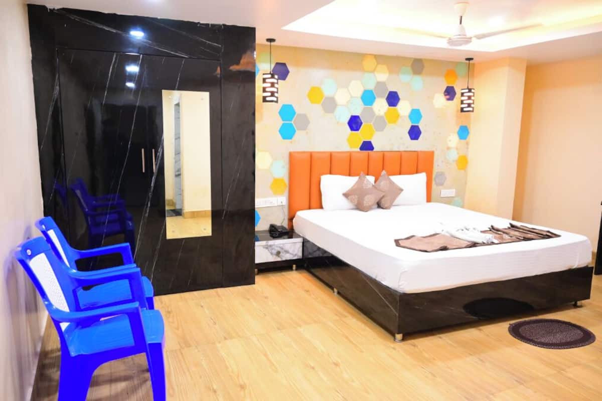 A bedroom with a bed, a nightstand, a blue chair, and a wall with hexagonal patterns.