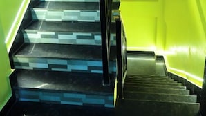 A staircase with alternating black and grey steps, surrounded by walls painted in bright yellow. - DhamStay Hotel Santosh Inn Near Temple (Puri)