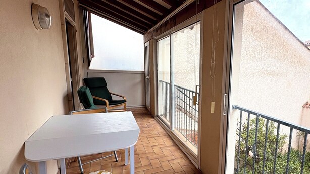 A balcony with a table and chairs, a view of the outside, and a railing.