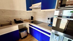 A compact kitchen with blue cabinets, a stainless steel oven, and a coffee maker.