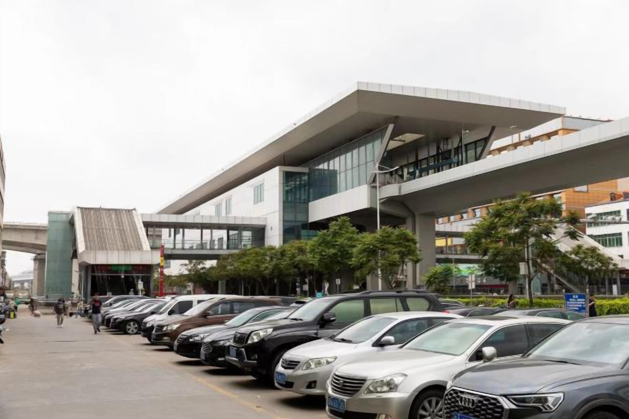A row of parked cars in front of a modern building with a flat roof and large windows.