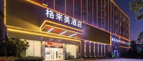 Un hotel con fachada moderna, señalización iluminada y un área de entrada bien cuidada.