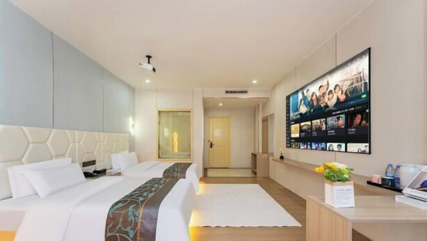 A hotel room with a large bed, a desk with a computer, and a TV displaying multiple screens. - Guangzhou Gelaimei Hotel (Zhuliao Subway Station) (Guangzhou)
