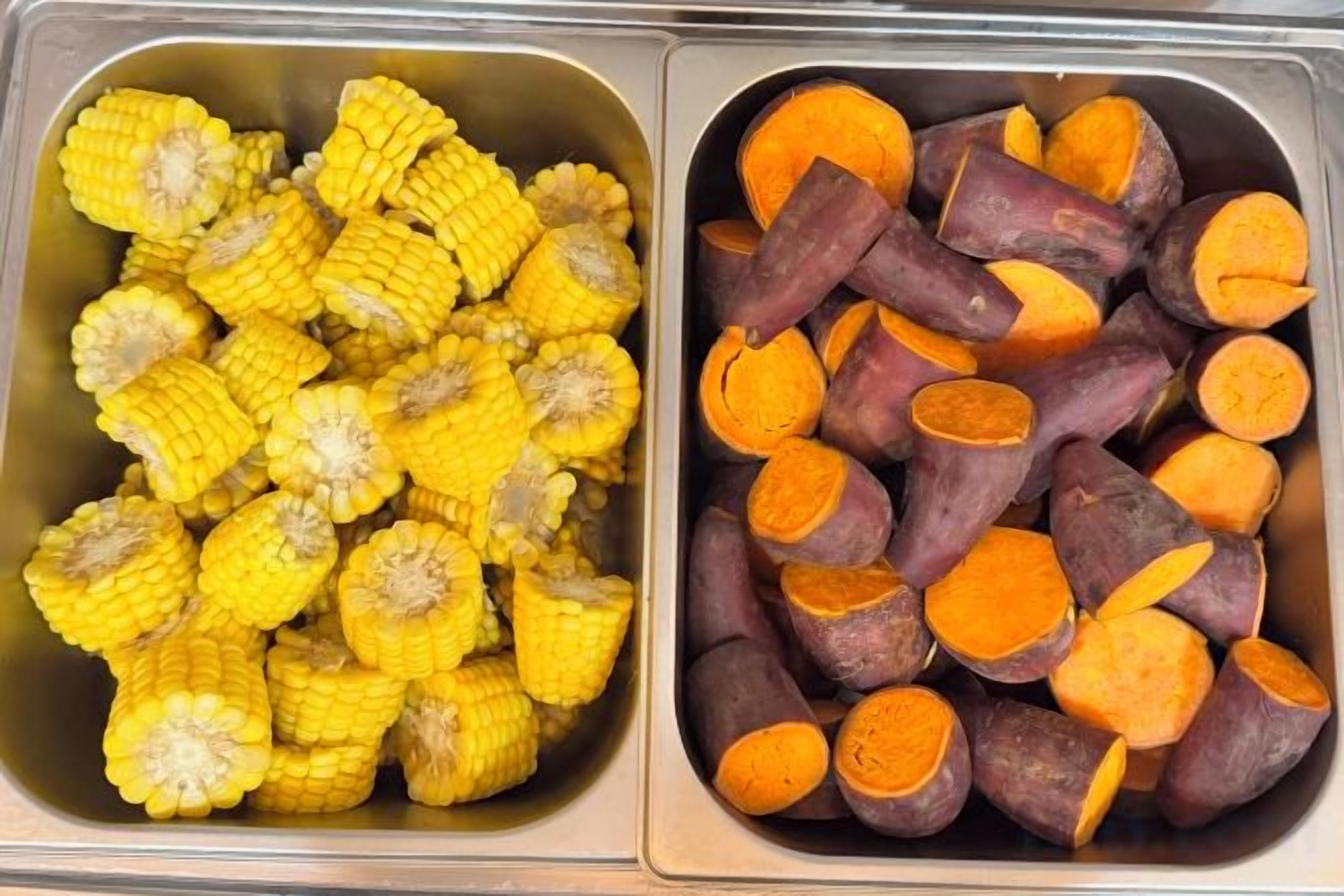 Two food containers, one with corn and the other with sweet potatoes.