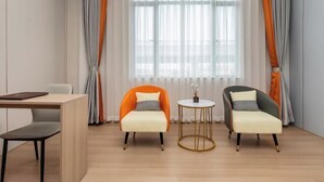 A modern room with two armchairs, a small round table, and a desk with a chair. - Guangzhou Gelaimei Hotel (Zhuliao Subway Station) (Guangzhou)