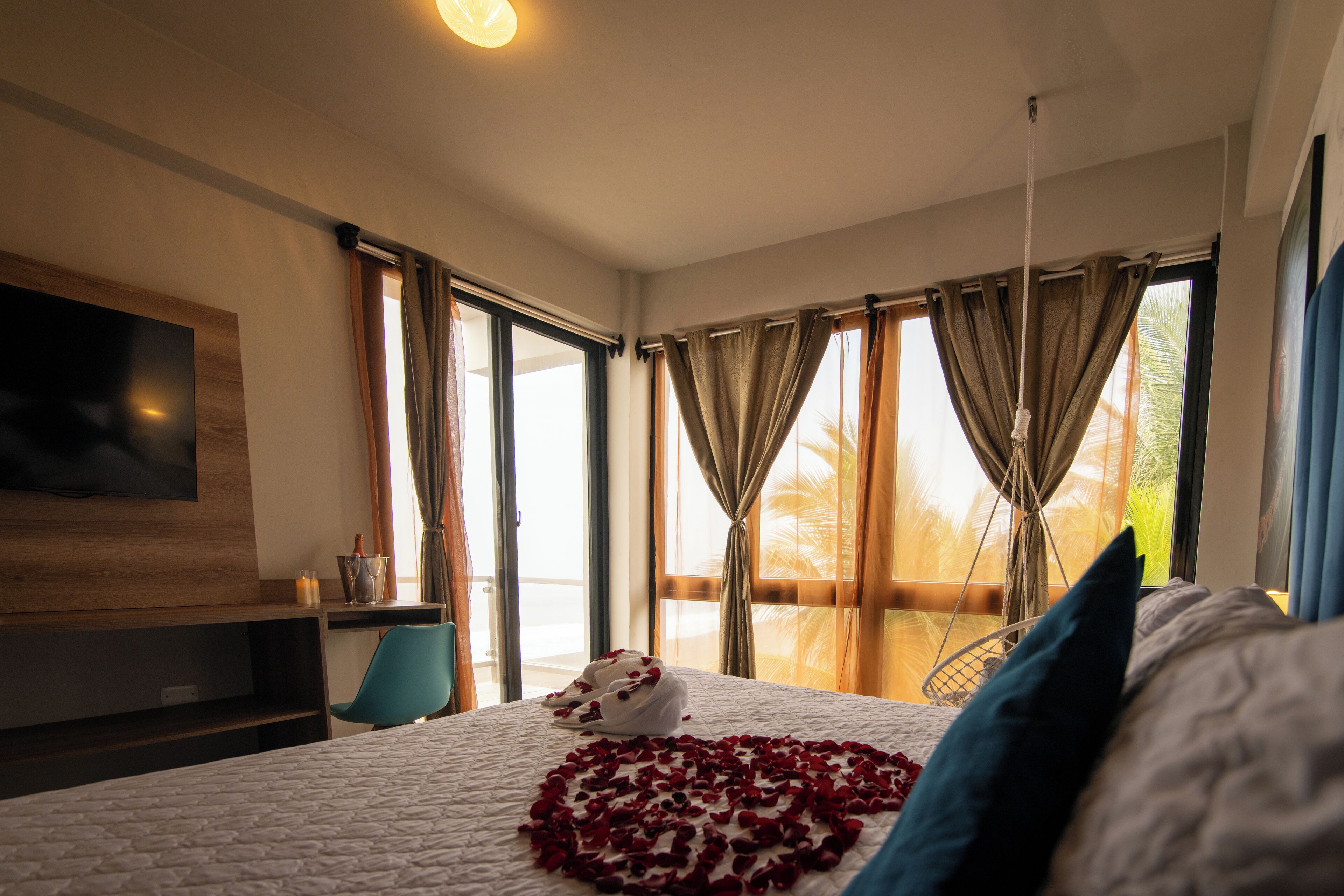 Habitación de hotel con una cama grande, televisor montado en la pared, balcón con vistas y escritorio con silla.