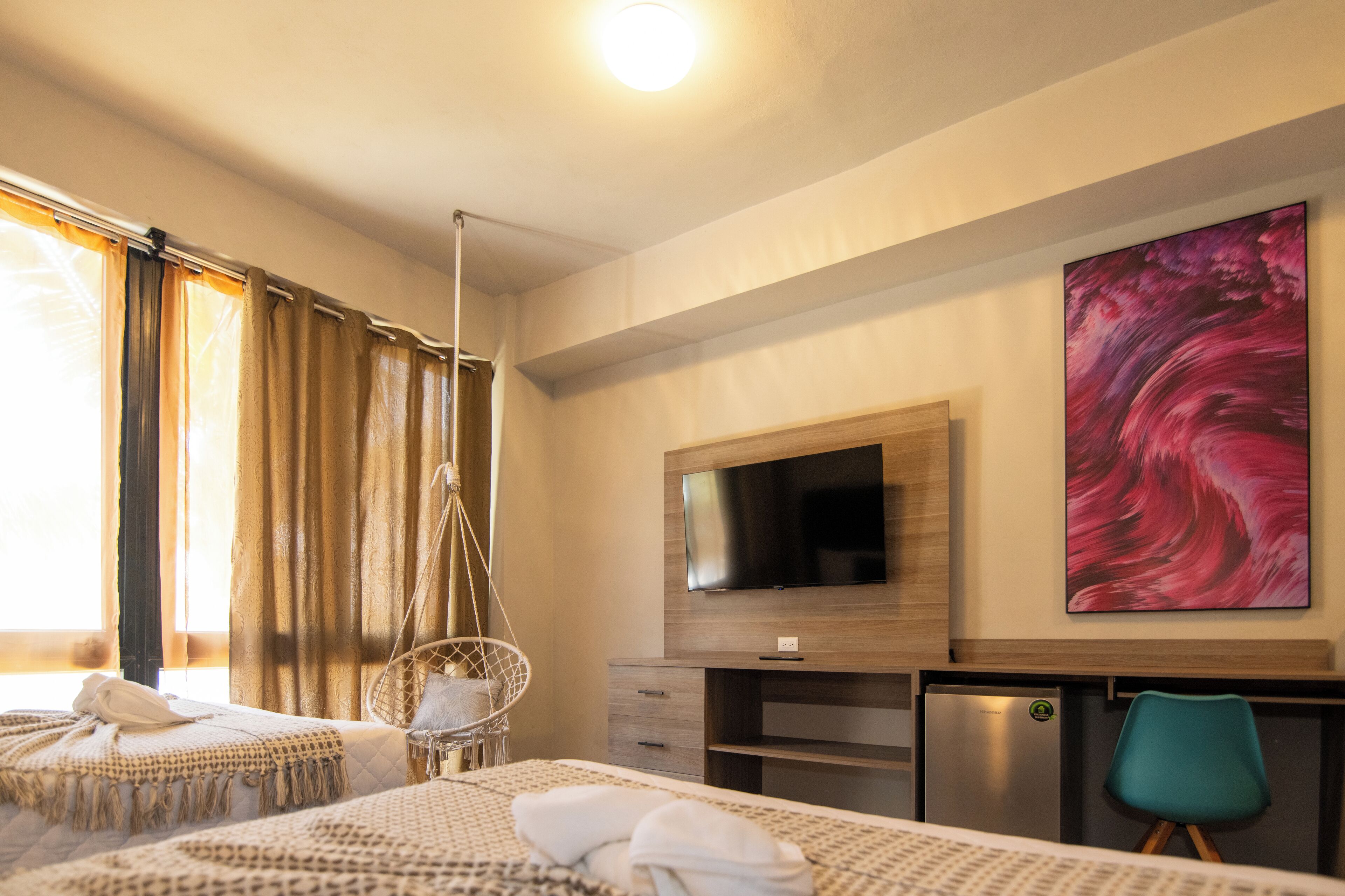 Habitación de hotel con dos camas, televisor, escritorio y un cuadro grande.