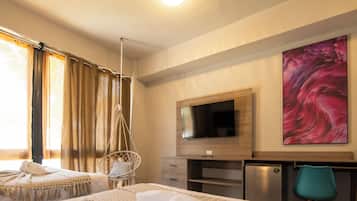 Habitación de hotel con dos camas, televisor, escritorio y un cuadro grande.