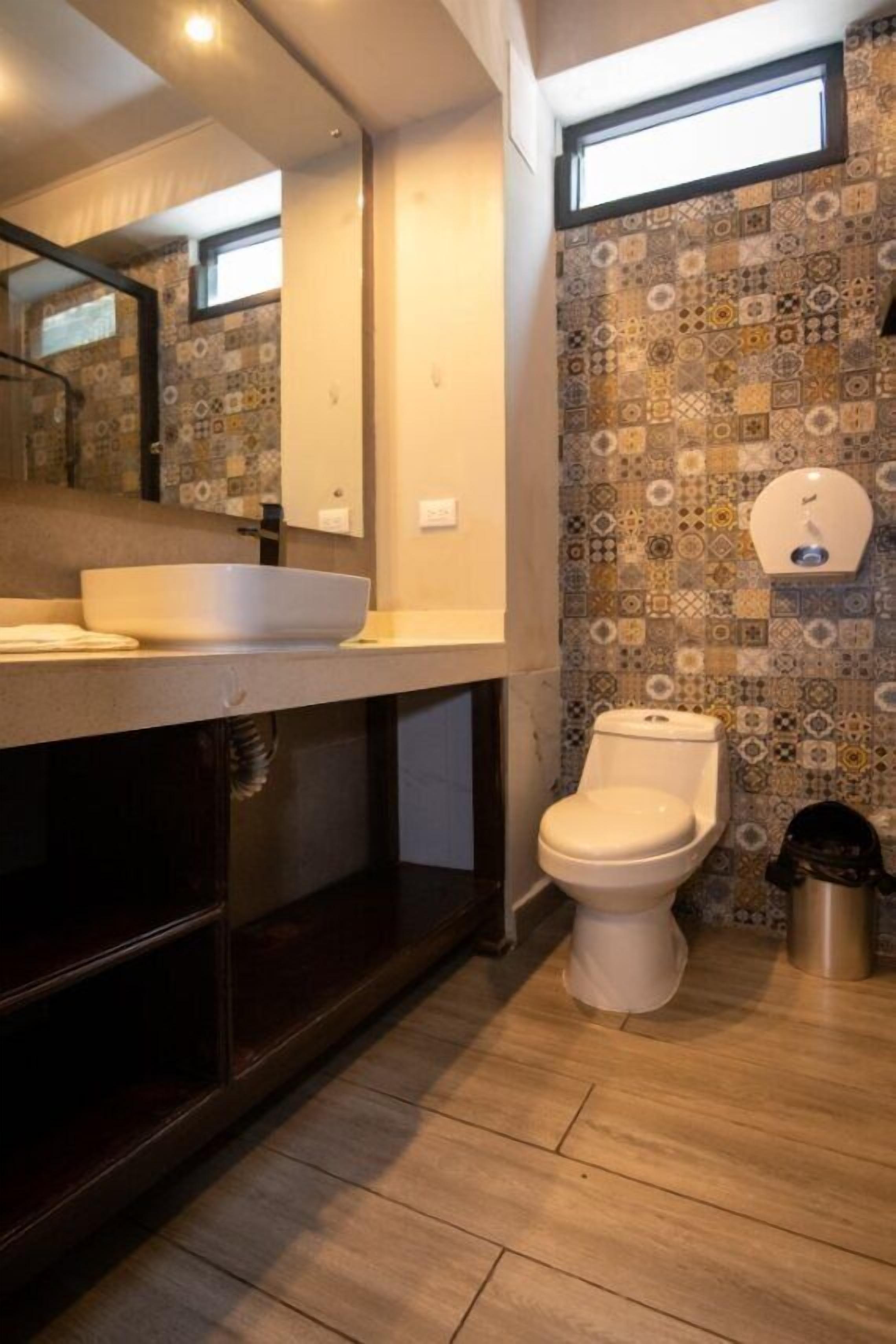 Een moderne badkamer met een grote spiegel, een wastafel, een toilet en een behang met patroon.