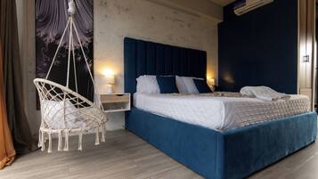 Un dormitorio con cama, mesitas de noche, una silla colgante y aire acondicionado instalado en la pared.