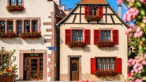 A traditional European building with multiple windows, red shutters, and flower boxes. - La Maison Céleste in Bergheim (Bergheim)