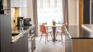 Et moderne køkken med en central ø, rustfrie stålgadgetter, samt et spiseområde med et rundt bord og stole.