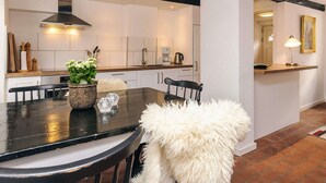 Una cocina moderna con armarios blancos, encimera negra y una isla central con una silla blanca de felpa.