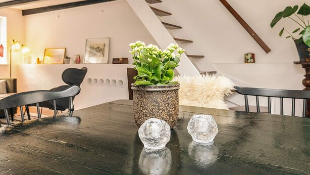 Un interior moderno con una mesa de madera, una planta en maceta y una escalera.
