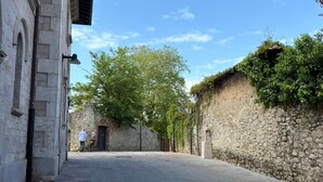 A paved street with stone walls, a building with arched windows, and a clear blue sky. - Apartment Centro y Mar in Llanes (Llanes)