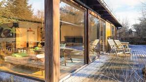 A modern house with large glass windows, a wooden deck, and outdoor furniture. - 4 Star Holiday Home in Albaek (Aalbaek)