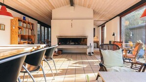 A modern interior with a fireplace, wooden ceiling, and a bookshelf. - 4 Star Holiday Home in Albaek (Aalbaek)