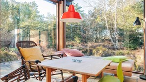 A cozy room with a large window, wooden furniture, and a red pendant light. - 4 Star Holiday Home in Albaek (Aalbaek)