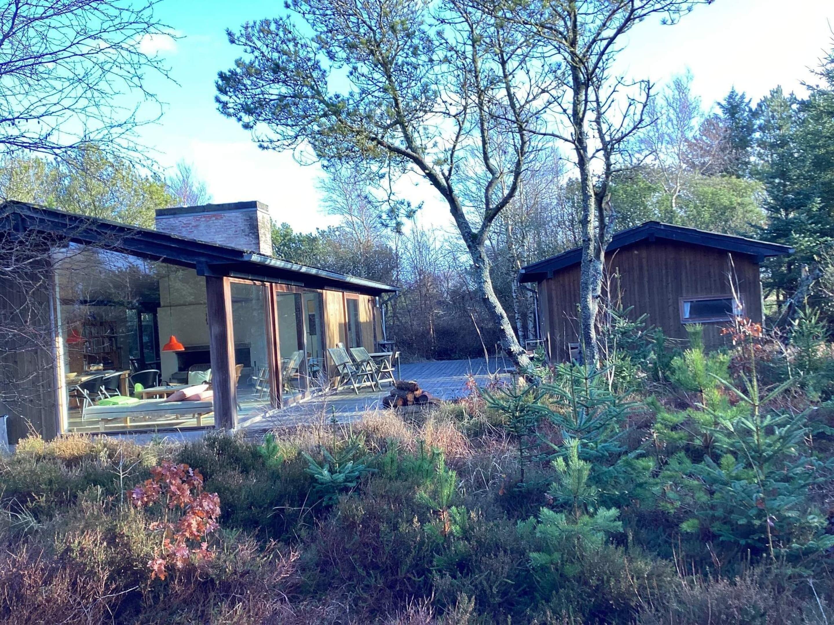 Une cabane moderne dotée d’un patio entièrement vitré et d’une structure en bois séparée.