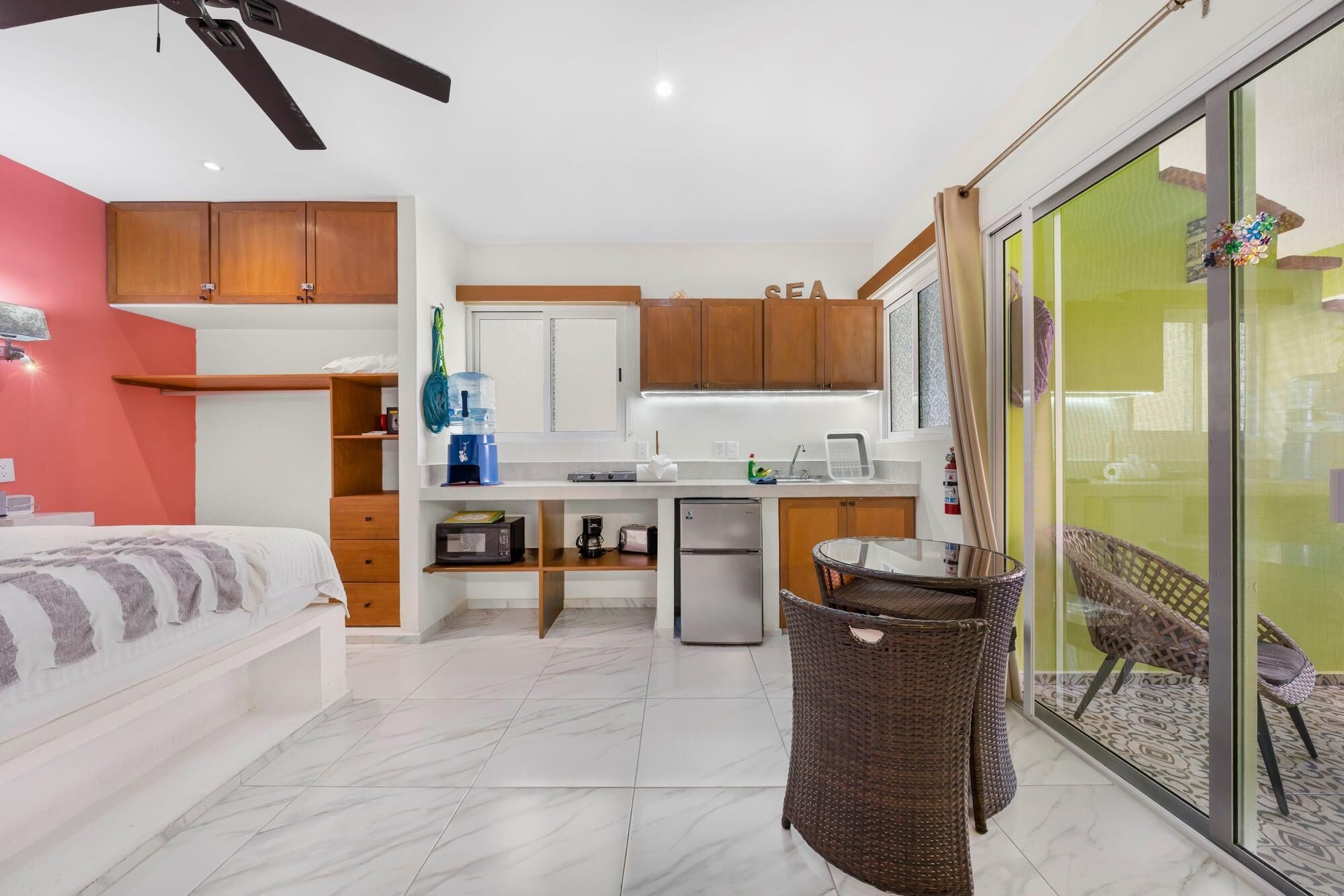 Cocina compacta con muebles de madera, dispensador de agua y un refrigerador pequeño.
