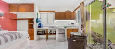 Cocina compacta con muebles de madera, dispensador de agua y un refrigerador pequeño.