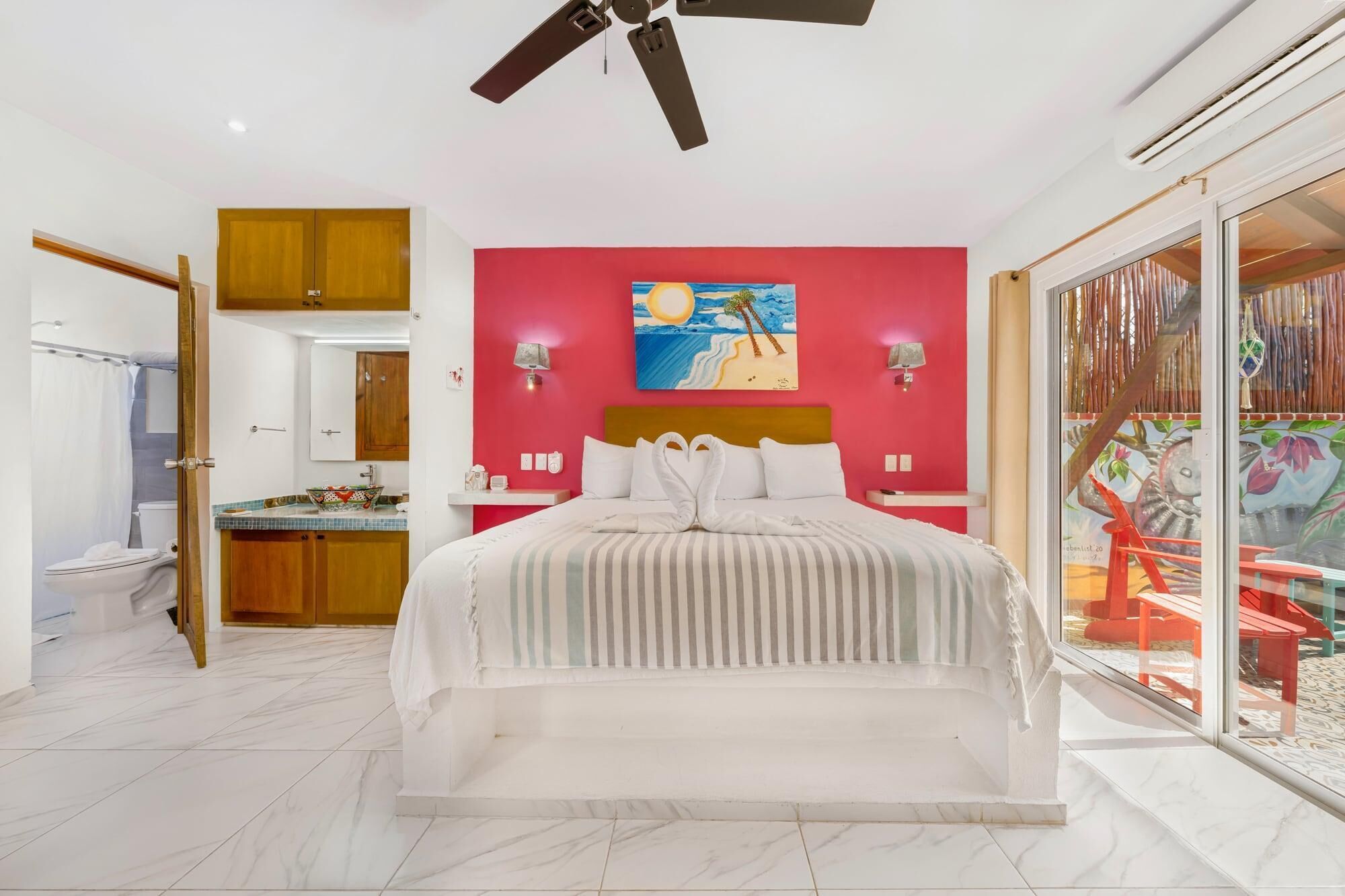 Ein Hotelzimmer mit Bett, Bad, einem Balkon mit Blick und Deckenventilator.