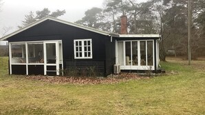 A small, single-story house with a black exterior and white trim. It features a large window and a door on the front, and a chimney on the side. - 5 Person Holiday Home in Vaeggerlose (Vaeggerlose)