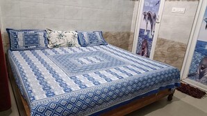 A bed with a patterned bedspread and pillows, a wooden headboard, and a wall with a dolphin mural. - DhamStay Hotel Glory Near Golden Beach (Puri)