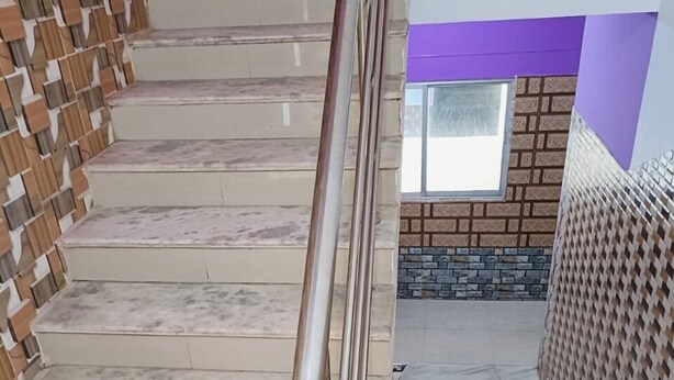 A marble staircase with metal handrails, leading to a room with a purple accent wall and a window. - DhamStay Hotel Glory Near Golden Beach (Puri)
