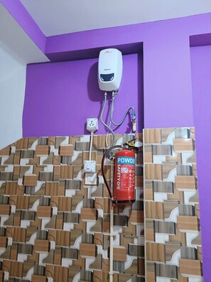 Een badkamer met een paarse muur, een decoratief patroon op de muur, een handdroger en een brandblusser.