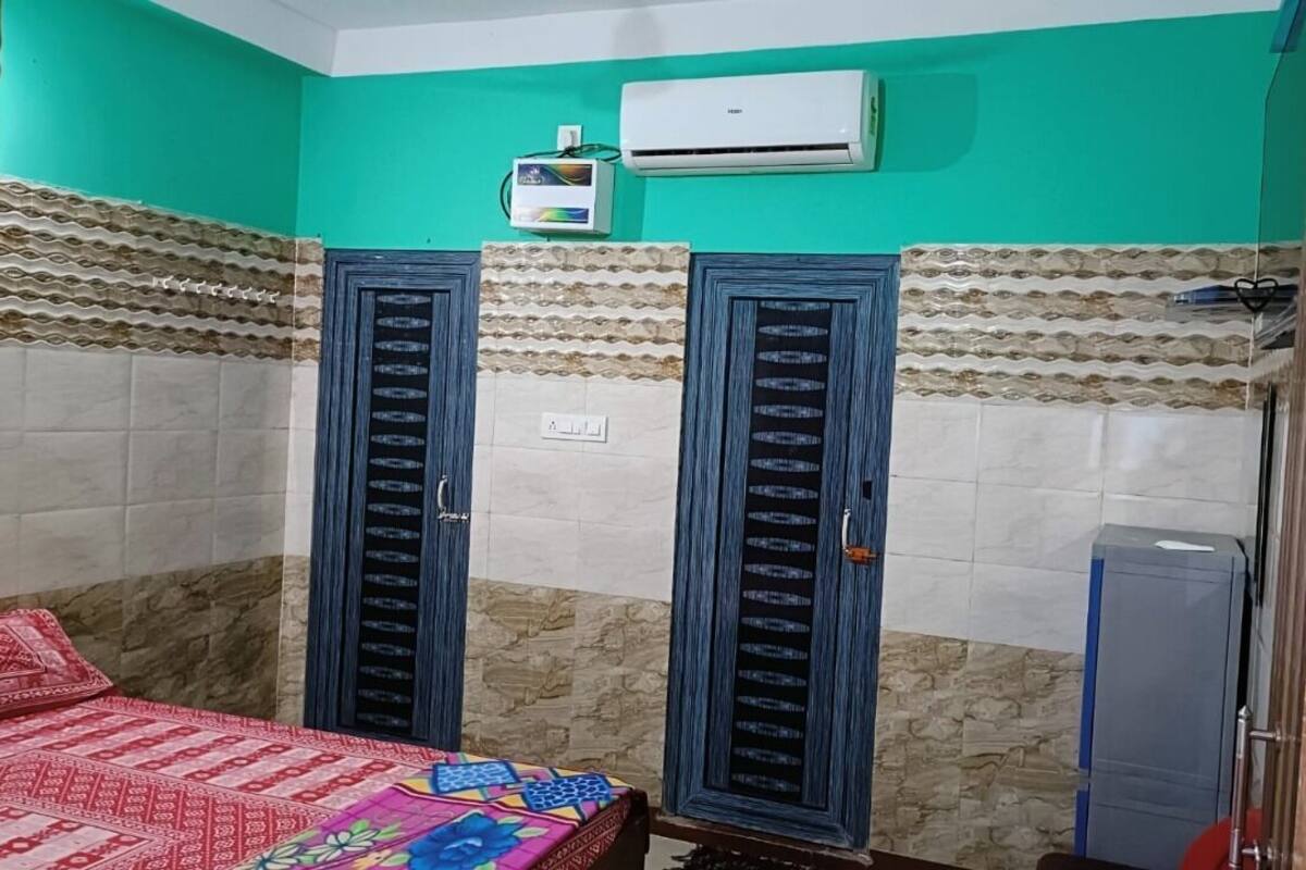 Een kamer met twee deuren, een bed met een bedovertrek met patroon, een airconditioner en een kleine verwarming.