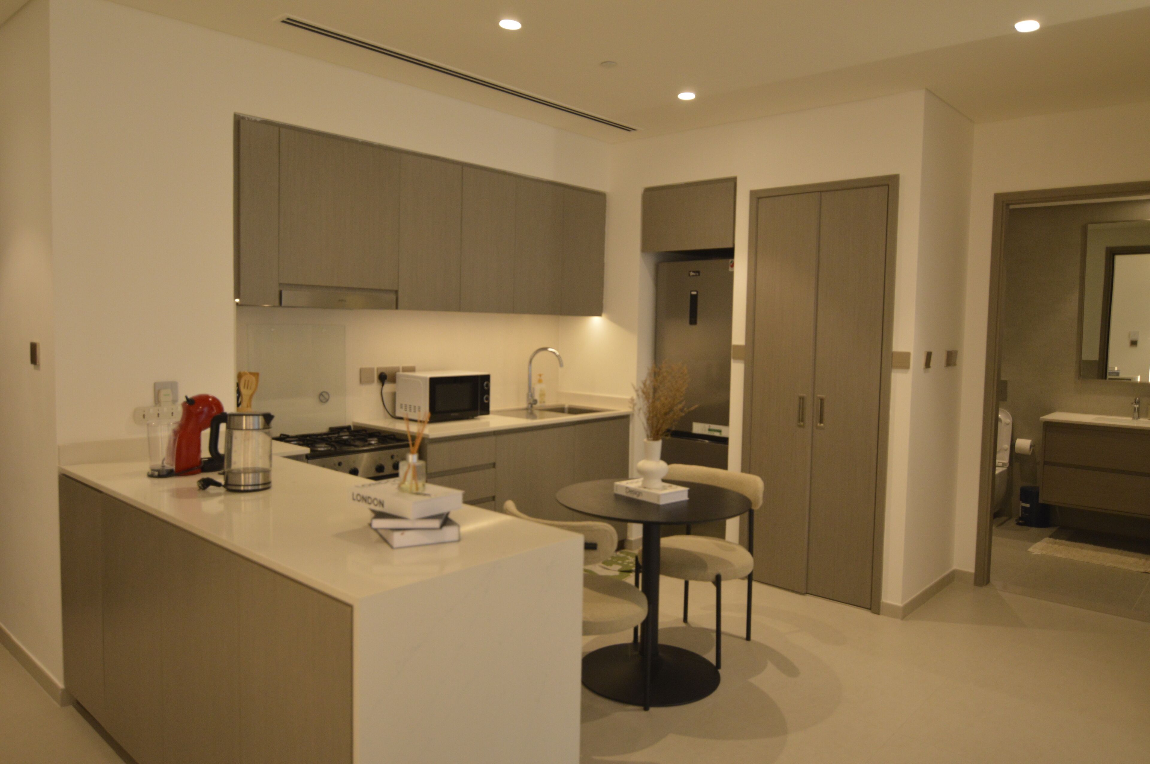 A modern kitchen with a central island, built-in appliances, and a dining area with a round table and chairs.