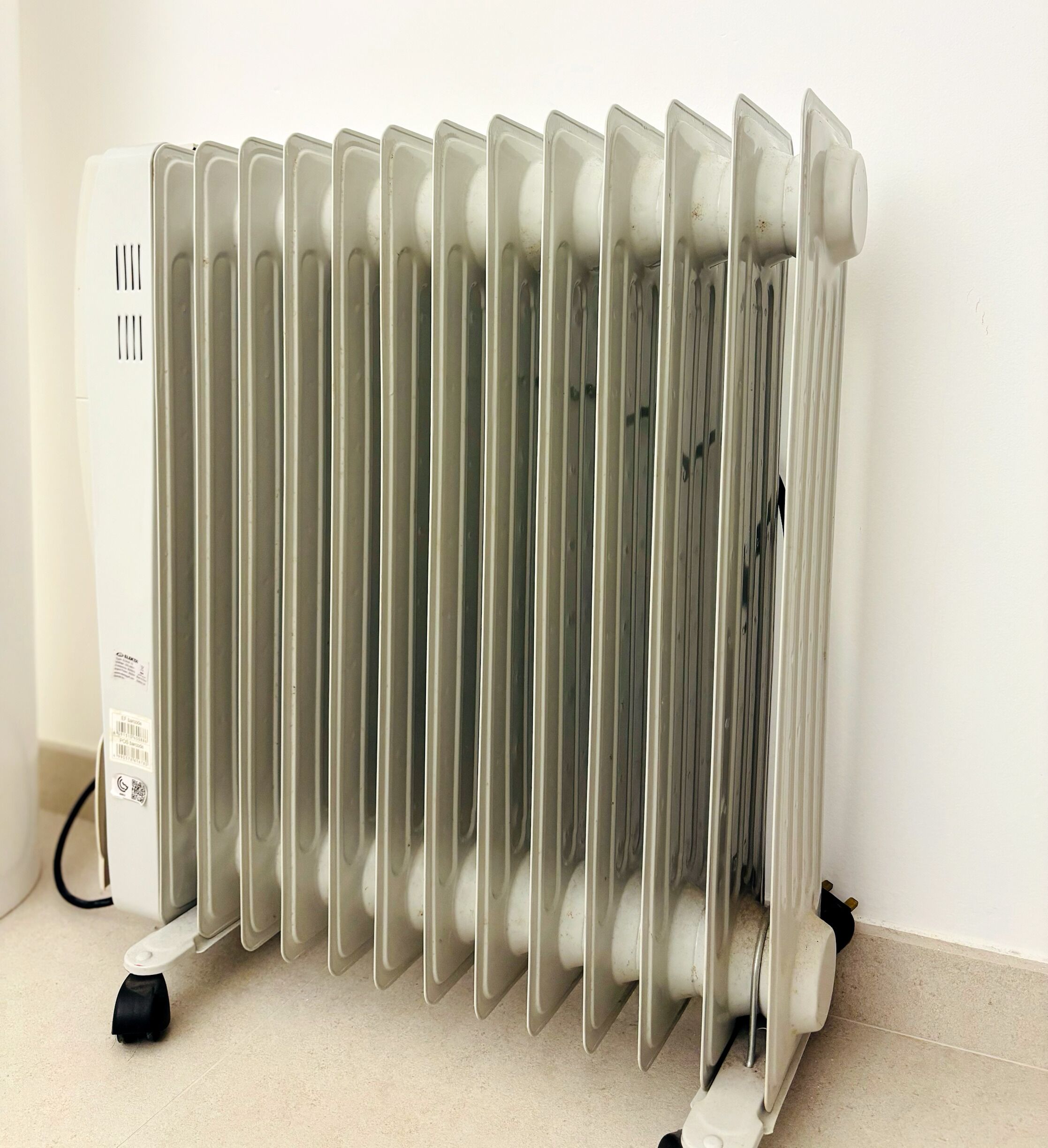 A white radiator with a control panel on the left side and a black base.
