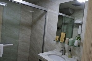 A bathroom with a glass shower enclosure, a marble sink, and a mirror with shelves holding toiletries. - Yiyun Boutique Hostel (Shanghai Zhujiajiao) (Shanghai)