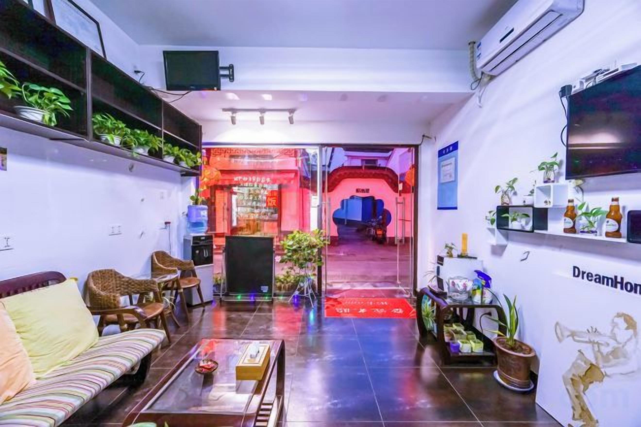 Un hall de hotel con un sofá, sillas, una mesa de centro y un televisor en la pared.